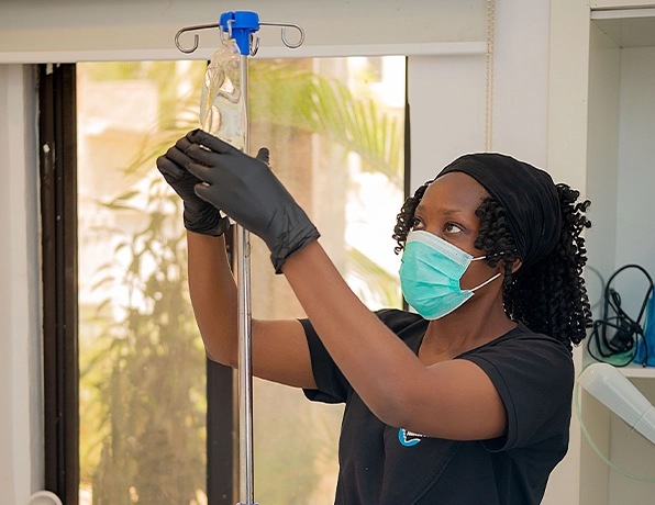 Nurse preparing a vitamin IV drip bag on a stainless steel stand at a wellness clinic