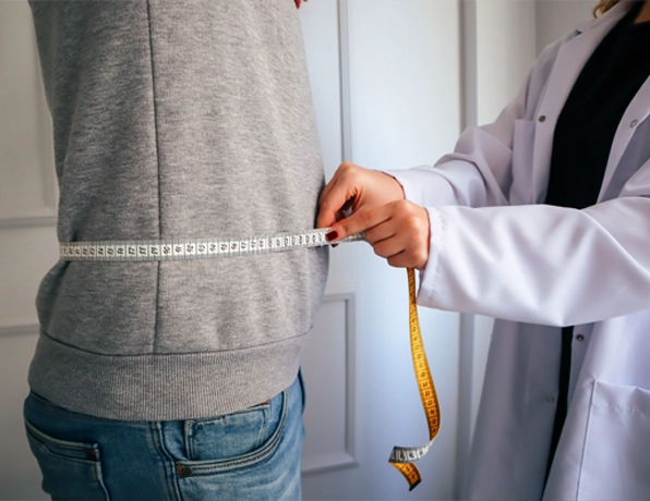 Doctor measuring a patient's waist with a tape measure during a weight management consultation at Optimum Sports & Wellness Institute in Polokwane